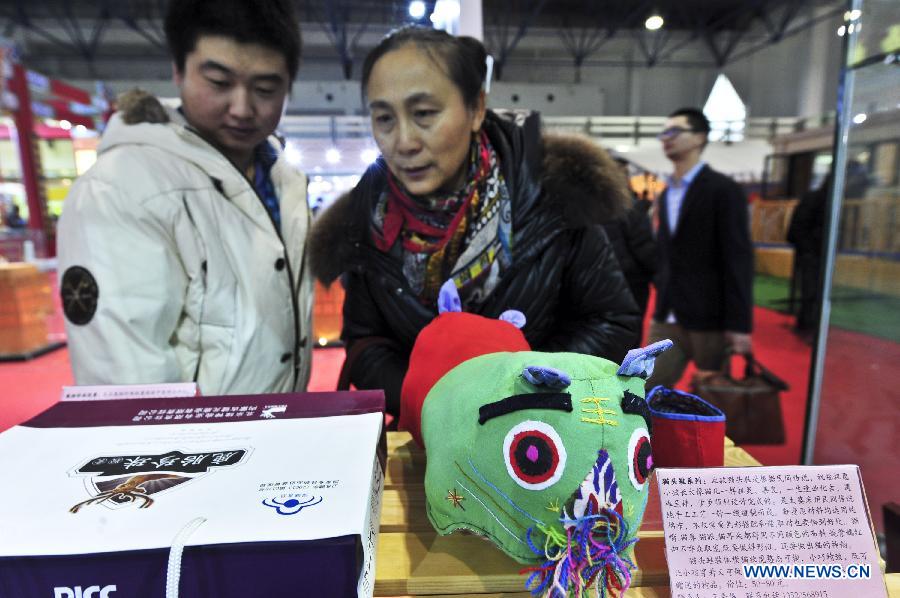 Visitors look at a tiger pillow at the 2012 Beijing Tourism Product Expo in Beijing, capital of China, Dec. 28, 2012. The four-day expo was opened Friday at the China International Exhibition Center in Beijing. Tourism souvenirs, craftworks, business gifts, outdoor gears and cultural and creative products from about 1,000 exhibitors were demonstrated at the event. (Xinhua/Wang Jingsheng)