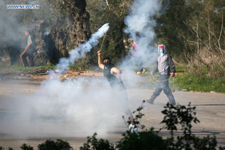 A Palestinian protester throws stones at Israeli soldiers during a protest against the expanding of Jewish settlement in the West Bank village of Nabi Saleh, near Ramallah, on Dec. 28, 2012. (Xinhua/Fadi Arouri) 