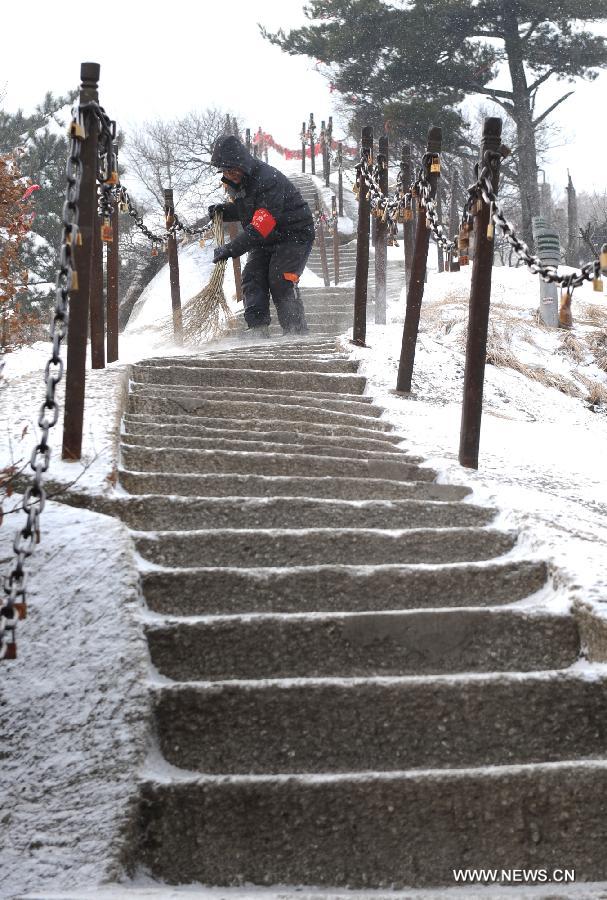 Workers clean snow off stairs in Huashan Mountain, a famous tourism destination in north China's Shaanxi Province, Dec. 28, 2012. (Xinhua/Tao Ming)