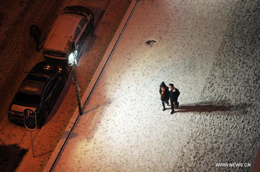 Citizens walk on a snow-covered road in Beijing, capital of China, Dec .28, 2012. A snowfall hit Beijing on Friday evening. (Xinhua/Lu Yan)