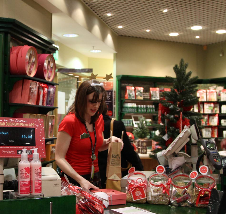 A saleswoman wraps for the customer in a mall in Edinburgh, Britain on Dec. 22, 2012. To attract more customers, many shopping centers in Edinburgh have offered pre-Christmas discounts.(Xinhua/Guo Chunju)