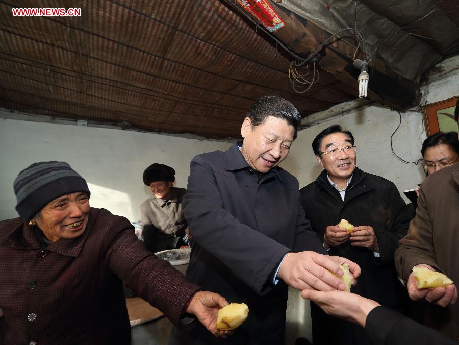 Xi Jinping (C), general secretary of the Communist Party of China (CPC) Central Committee and chairman of the CPC Central Military Commission, tastes steamed potatoes while visiting the family of Tang Rongbin (back), an impoverished villager in the Luotuowan Village of Longquanguan Township, Fuping County, north China's Hebei Province, Dec. 30, 2012. Xi made a tour to impoverished villages in Fuping County from Dec. 29 to 30, 2012. (Xinhua/Lan Hongguang) 