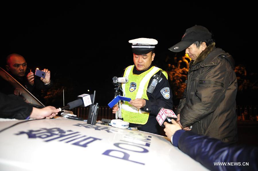 A policeman writes a ticket to a driver in Shenzhen, south China's Guangdong Province, Jan. 1, 2013. The revised traffic regulation takes effect on Tuesday. According the new rules, 52 different sorts of violations can result in deducting points for punishment, up from 38 under the previous regulation. (Xinhua/Liang Xu) 