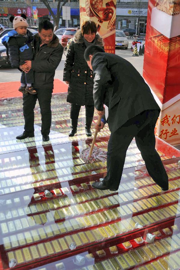A staff member sweeps the "gold road," on which 1,000 pieces of 1,000-gram gold bars are laid beneath toughened glass, in a gold shop in Binzhou City, east China's Shandong Province, Jan. 1, 2013. (Xinhua/Zhang Binbin) 