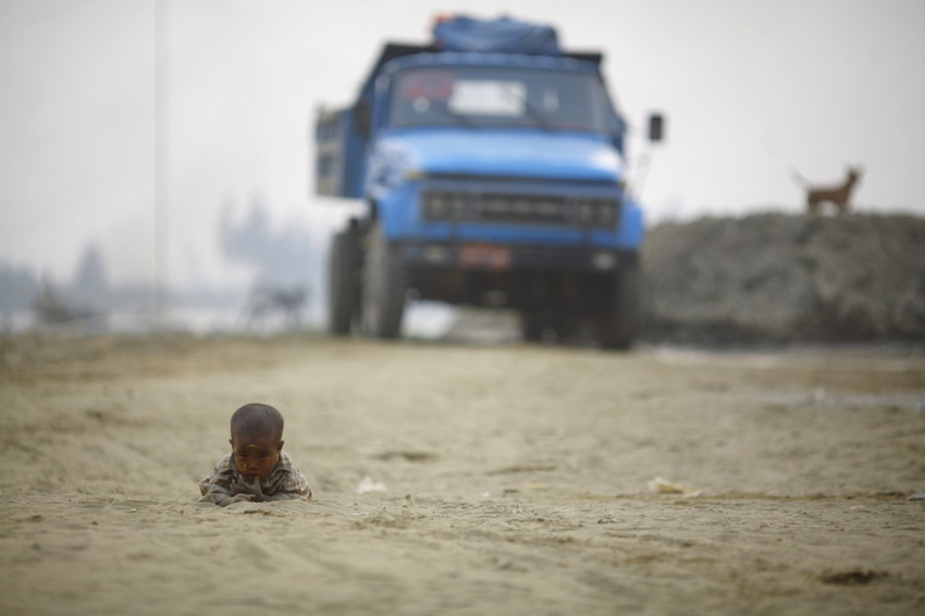 A kid plays on the road near the bank of the Yangon river on March 17， 2012. (Photo/Reuters)