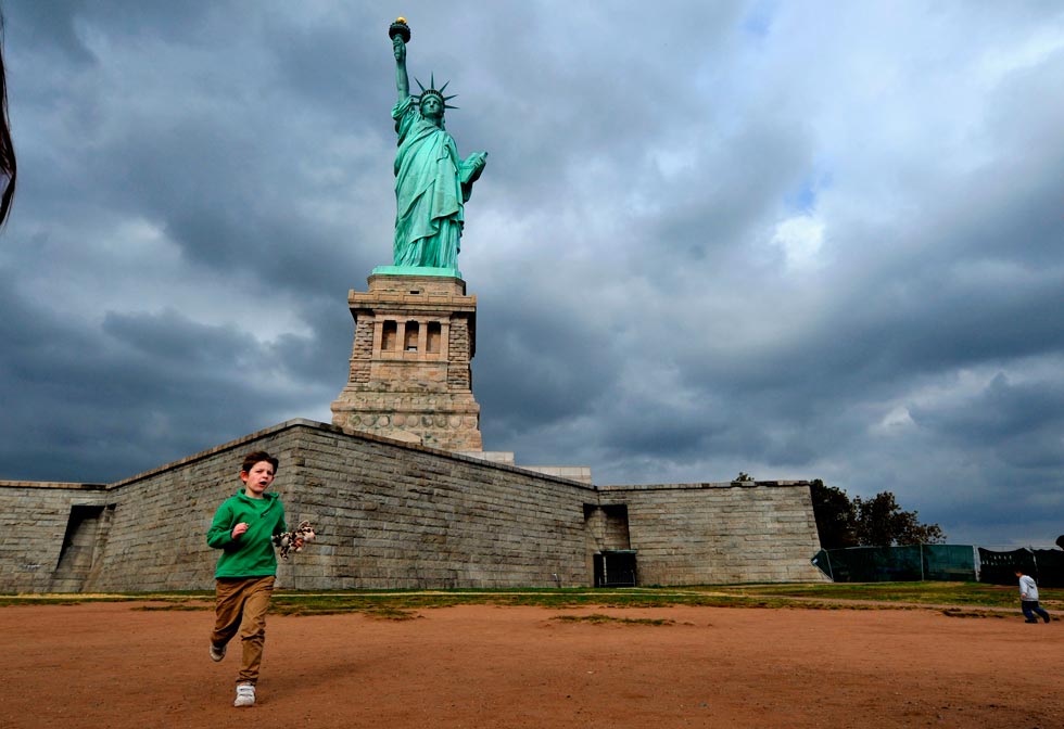 A boy plays around the Statue of Liberty in New York on Oct. 27, 2012. The crown of the Statue of Liberty will reopen to the public on Sunday after a year-long renovation to its interior. (Photo/Xinhua) 