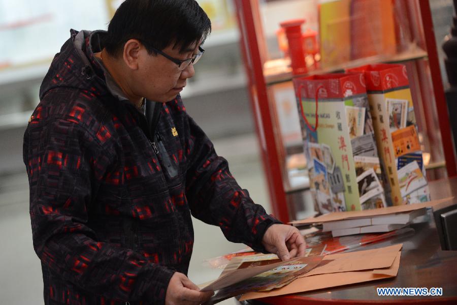 A citizen checks his stamps featuring a cartoon snake at a post office in Macao, south China, Jan. 3, 2013. (Xinhua/Cheong Kam Ka) 