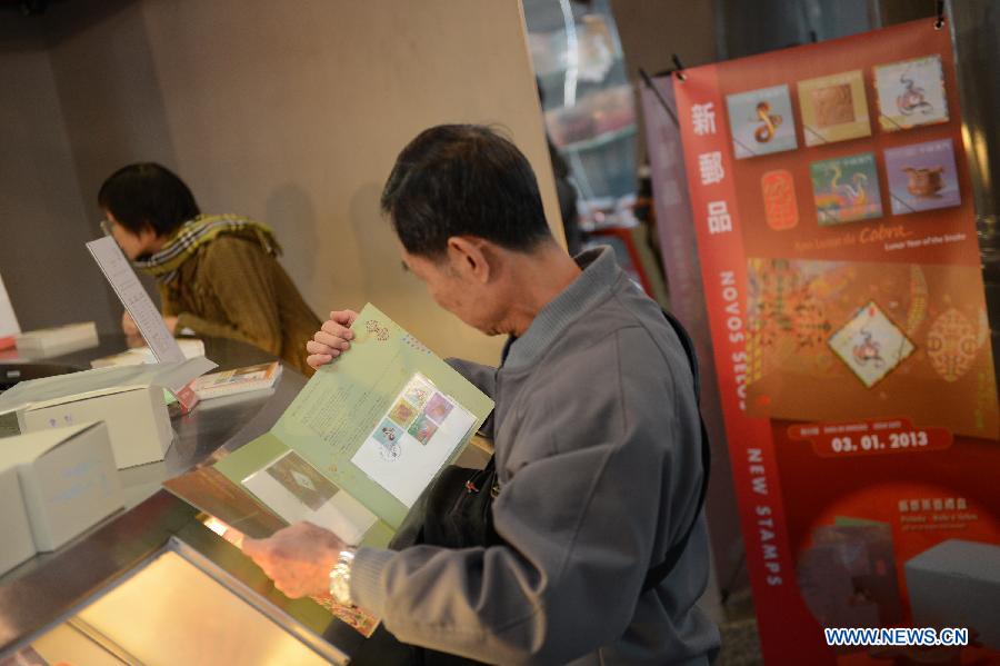 A citizen selects the stamps featuring a cartoon snake at a post office in Macao, south China, Jan. 3, 2013. (Xinhua/Cheong Kam Ka) 