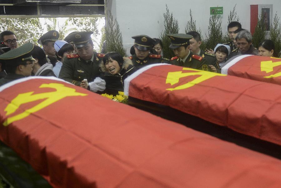 Relatives of the deceased firefighters who lost lives in a rescue operation on Jan. 1 at the Hangzhou Yusei Machinery Co., Ltd wail in front of coffins during memorial meeting in Hangzhou, capital of east China's Zhejiang Province, Jan. 4, 2013. (Xinhua/Han Chuanhao) 
