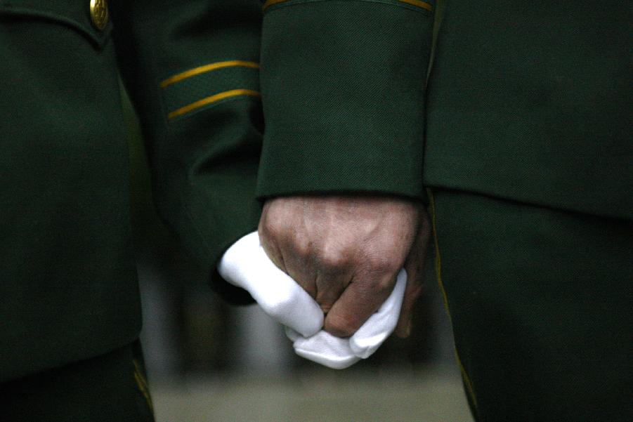 Hands of two soldiers tightly fasten as they attend the memorial meeting for the deceased firefighters who lost lives in a rescue operation on Jan. 1 at the Hangzhou Yusei Machinery Co., Ltd in Hangzhou, capital of east China's Zhejiang Province, Jan. 4, 2013. (Xinhua/Cui Xinyu) 