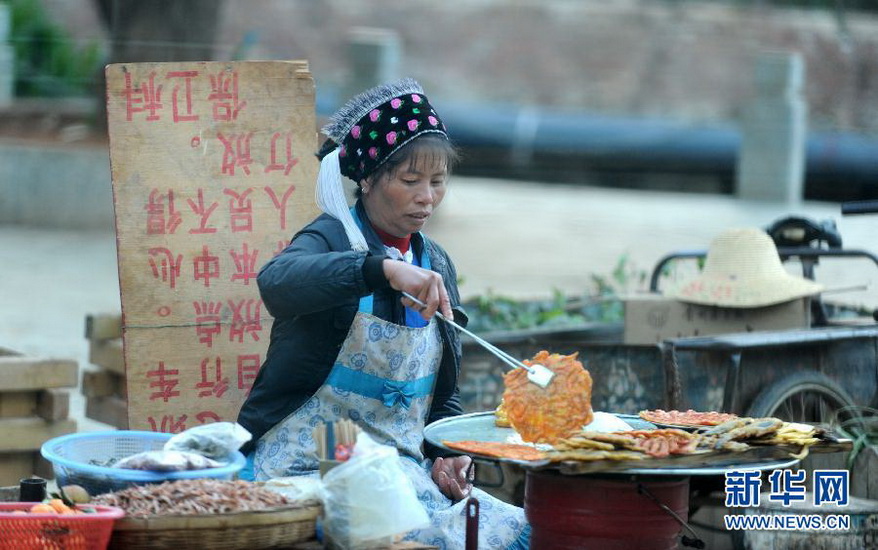 A woman of Bai nationality sells self-made deep fried snacks in Shuanglang Dali, Yunnan on Dec.11, 2012. Shuanglang boasting of charming natural beauty attracts thousands of visitors. Tourism is a burgeoning industry which attracted more than 100,000 visitors during the golden week during the National Day. (Xinhua/Qin Qing)