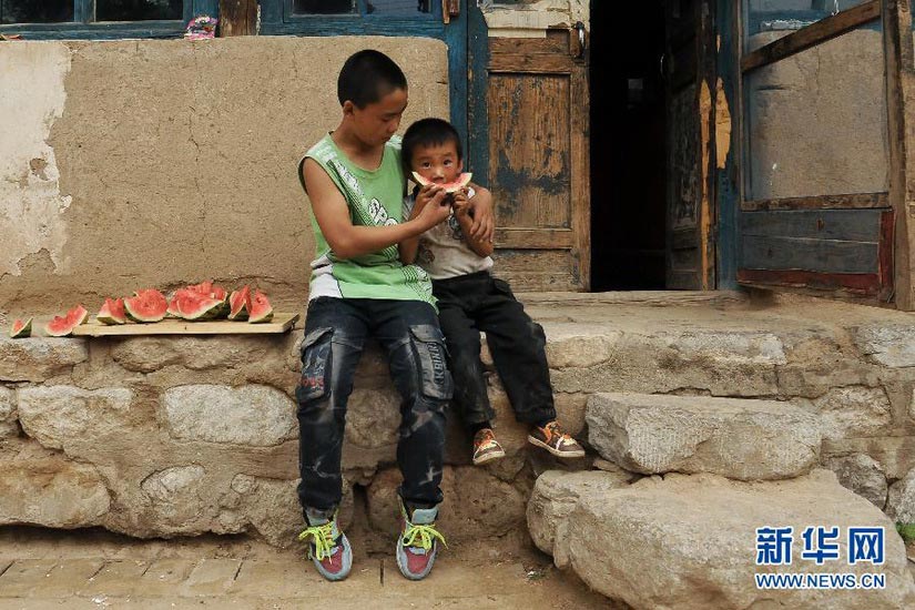 Enjoying Watermelon:The 5-year-old Zhan Xu and his 15-year-old brother Zhan Wei enjoy watermelon on July 24, 2012. Zhan Wei is one of the lucky children who receive help from “Realizing Your Dream”, a group of college students and professors from Taiyuan Institute of Technology. The “Realizing Your Dream” is now helping 220 students who are orphans or from single-parent family. (Xinhua/ Fan Minda)