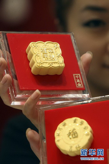 A salesgirl is showing a special moon cake made of gold in a gold shop in Yantai, Shandong Province on Sept. 12, 2012. As the Chinese traditional mid-autumn was approaching, gold shops displayed and began to sell vivid gold moon cake. (Xinhua/Shen Jizhong)
