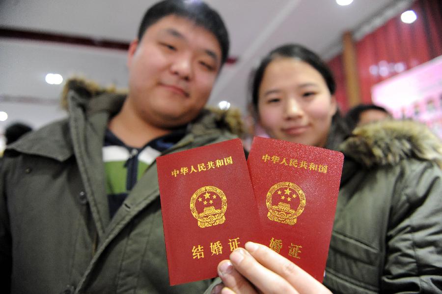 A couple show their marriage certificates at the marriage registration office in Zhengzhou, capital of central China's Henan Province, Jan. 4, 2013. Quite a number of couples flocked to tie the knot on Jan. 4, 2013, or 2013/1/4, which sounds like "Love you forever" in Chinese. (Xinhua/Li Bo)