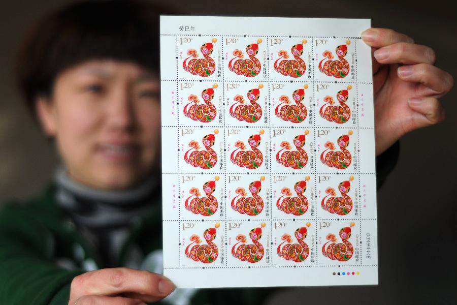 A staff member shows a full page of "year of snake" stamps at Binzhou Post Office in Binzhou, east China's Shandong Province, Jan. 4, 2013. The lunar year 2013 is the "Year of the Snake" in the Chinese zodiac. The stamp of "year of snake" will be released by China Post on Jan. 5. (Xinhua/Zhang Binbin)
