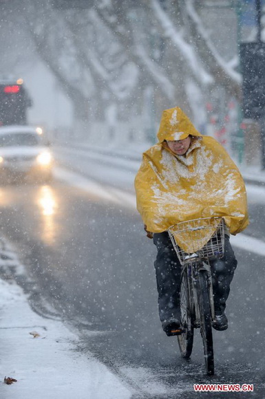 A citizen rides a bike against the snow on a road in Hangzhou, capital of east China's Zhejiang Province, Jan. 4, 2013. Many areas in Zhejiang received snowfalls on Friday. The local meteorological authority issued an orange alert for icy roads on Friday morning, warning the possible disruption which the continued snow might cause to traffic, power supply and agriculture. (Xinhua/Ju Huanzong)