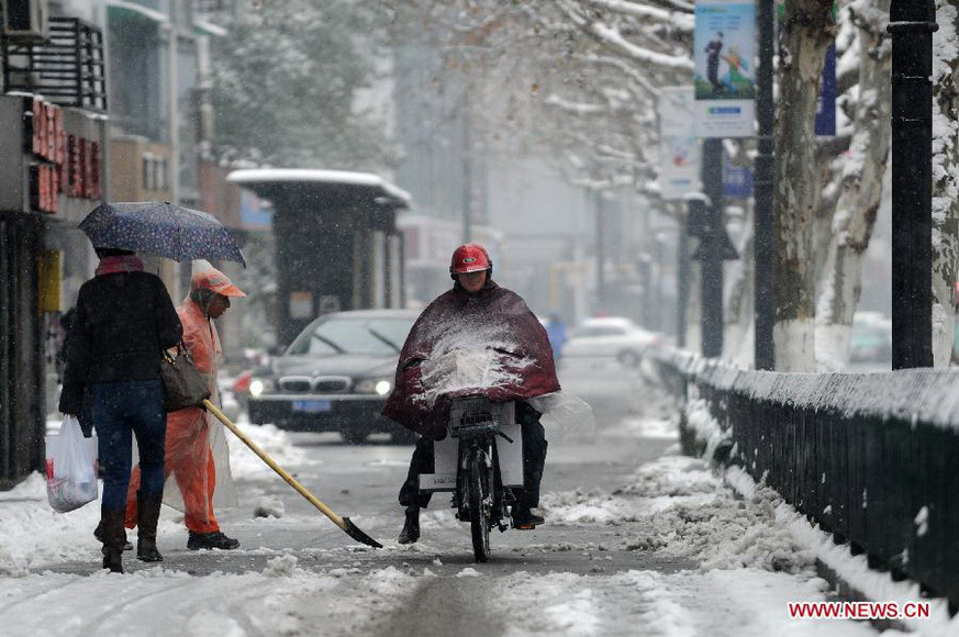 Citizens make their way on a snow-covered road as a sanitationman clears the snow in Hangzhou, capital of east China's Zhejiang Province, Jan. 4, 2013. Many areas in Zhejiang received snowfalls on Friday. The local meteorological authority issued an orange alert for icy roads on Friday morning, warning the possible disruption which the continued snow might cause to traffic, power supply and agriculture. (Xinhua/Ju Huanzong)