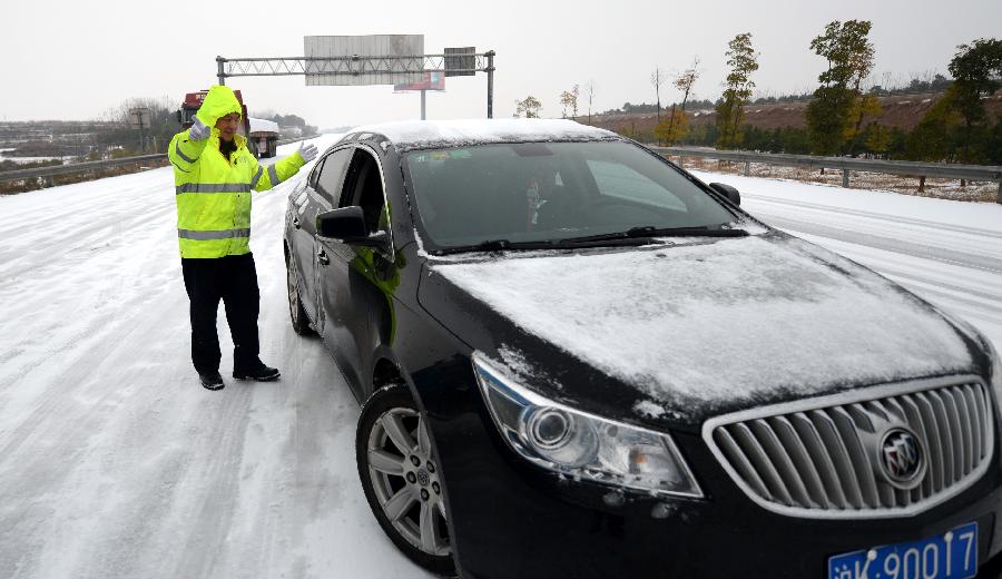 A policeman directs the traffic at the Changzhang section of the Shanghai-Kunming expressway in Nanchang, capital of east China's Jiangxi Province, Jan. 4, 2013. The snowfall which hit most areas of Jiangxi on Friday disrupted expressway traffic, causing several car accidents. (Xinhua/Zhou Ke)