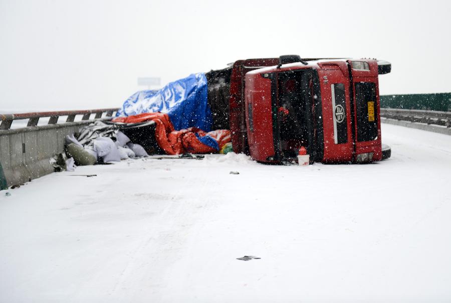 A truck overturns on the icy road at the Changzhang section of the Shanghai-Kunming expressway in Nanchang, capital of east China's Jiangxi Province, Jan. 4, 2013. The snowfall which hit most areas of Jiangxi on Friday disrupted expressway traffic, causing several car accidents. (Xinhua/Zhou Ke)