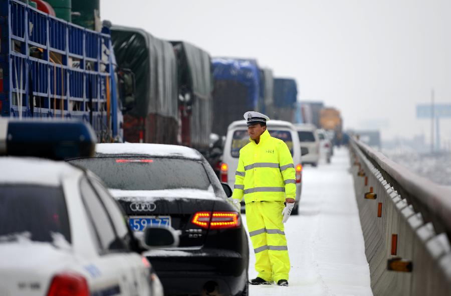 A traffic policeman tries to guide vehicles stranded on the Nanchang-Zhangshu section of the Shanghai-Kunming highway in east China's Jiangxi Province, Jan. 4, 2013. Vehicles were blocked in a traffic jam on the highway for a couple of hours due to a heavy snowfall in Jiangxi on Friday. (Xinhua/Zhou Ke)