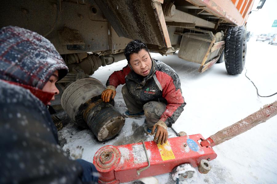 A driver repairs his truck amid snow on an icy road in Nanchang, capital of east China's Jiangxi Province, Jan. 4, 2013. Most highways in Jiangxi were frozen and some blocked due to the heavy snow since Thursday night. The provincial meteorological observatory issued an orange alert on icy road on Friday. (Xinhua/Zhou Ke)