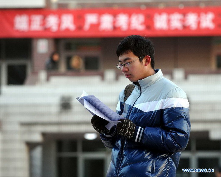 A candidate reviews a book before sitting the National Entrance Examination for Postgraduate (NEEP) outside North China University of Technology in Beijing, capital of China, Jan. 5, 2013. Examinees to take the exam on Jan. 5 are expected to hit a record high of 1.8 million this year. (Xinhua/Gong Lei)
