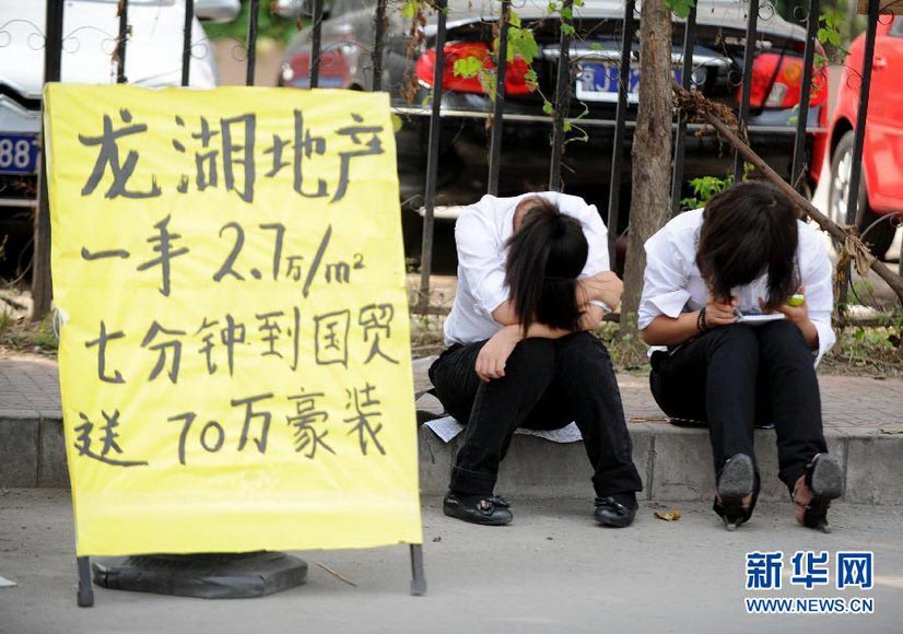 Two real estate agents waiting for clients get tired and sit by the roadside to have a rest outside a residential area in Chaoyangmen, Beijing, Sept. 8, 2012. (Xinhua/Luo Xiaoguang)