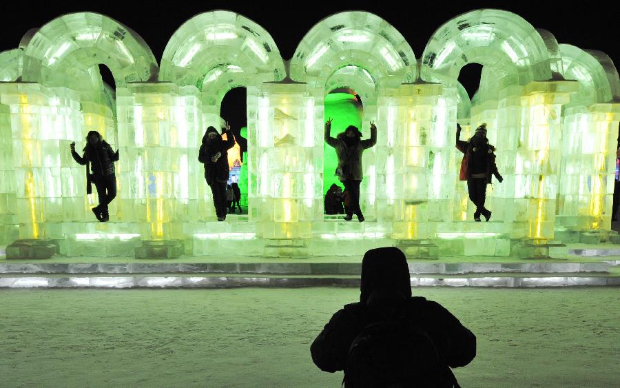 Visitors pose for photo by an ice sculpture in the Ice and Snow World during the 29th Harbin International Ice and Snow Festival in Harbin, capital of northeast China's Heilongjiang Province, Jan. 5, 2013. The festival kicked off on Saturday. (Xinhua/Wang Jianwei)
