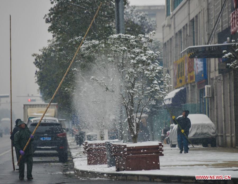 Sanitationmen clear the snow on the trees in Ji'an County, east China's Zhejiang Province, Jan. 4, 2013. Zhejiang Weather Bureau on Friday issued the first orange alert for road icing after the heavy snow and freezing weather since Thursday. (Xinhua/Xu Yu) 