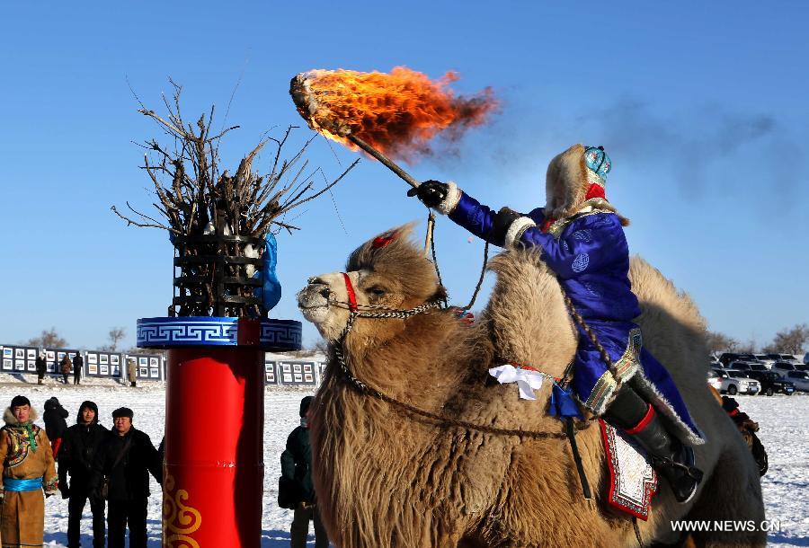 A herdsman lights a torch during a ceremony before camel racing in Xi Ujimqin Banner of north China's Inner Mongolia Autonomous Region, Jan. 5, 2012. A camel cultural festival kicked off here Jan. 5, which included camel racing, performance and training competition. (Xinhua/Ren Junchuan)