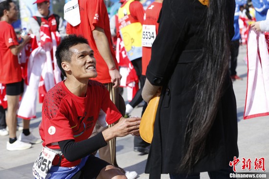 A man proposes to his girlfriend after finishing entire journey of 11th Xiamen International Marathon on Saturday morning. (Chinanews/ Du Yang)
