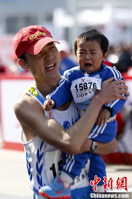 Father and son take part in the 11th Xiamen International Marathon on Saturday morning. (Chinanews/ Sheng Jiapeng)
