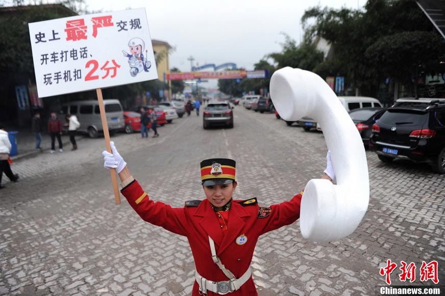 A staff holds up the banner reading “Use of cellphone is not allowed while driving, or you will lose two points” on the street of Chongqing, Jan. 5, 2013. (Xinhua/Chen Chao)