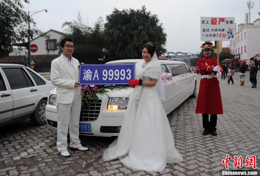 A staff holds up the banner reading “12 points deduction as punishment if the car plate number is shielded or stained” on the street of Chongqing, on Jan. 5, 2013. (Xinhua/Chen Chao)