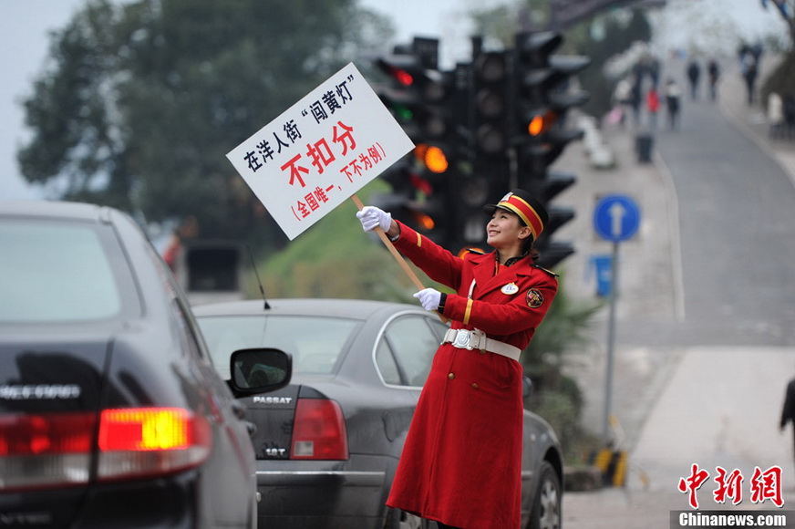 The photo taken on Jan. 5, 2013 shows a staff in military uniform holding the banner reading "Break yellow light, no point deduction (Won't be allowed next time, only in China)" to remind people the yellow traffic light means to slow down and prepare to stop. (Xinhua/Chen Chao)  