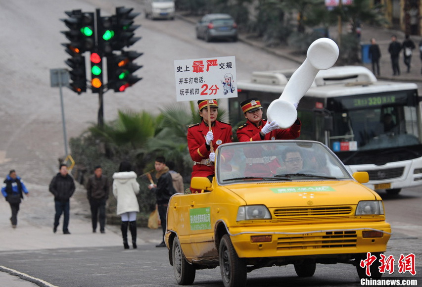 Staff wearing military uniform hold up the banner reading “Use of cellphone is not allowed while driving, or you will lose two points” on the street of Chongqing, Jan. 5, 2013.  (Xinhua/Chen Chao)