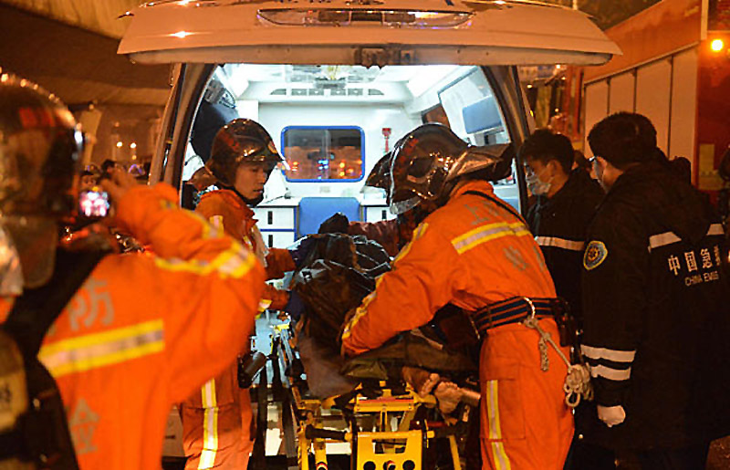 Firefighters carry one of the injured onto an ambulance after fire broke out at a farm produce wholesale market in Shanghai on Jan 6, 2013. (Photo/Xinhua)