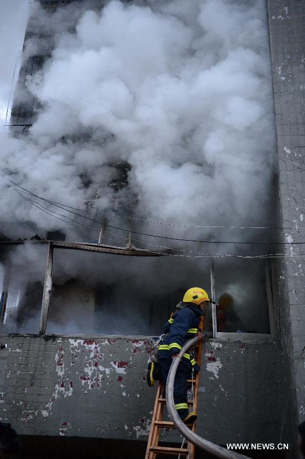 Firefighters get into a residential building on fire on the Honggu Road in Nanchang, capital of east China's Jiangxi Province, Jan. 6, 2013. A fire broke out on the first floor of the building on Sunday. No casualty is reported at present and the cause is still under investigation. (Xinhua/Zhou Mi)  