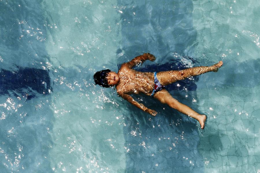 A kid swims in a pool in Sao Paulo, Brazil, on Jan. 6, 2013. Sao Paulo faces a hot weather with about 30 degrees centigrade these days. (Xinhua/AGENCIA ESTADO) 