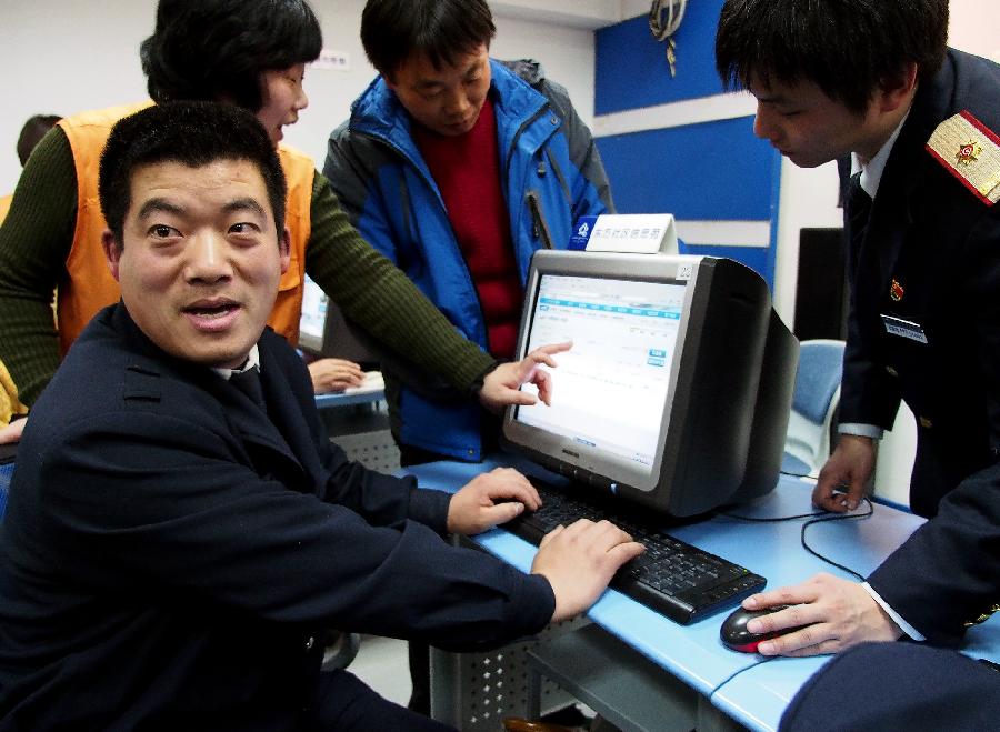 Liu Xiangrui (1st L), a migrant worker from Suqian in east China's Jiangsu Province, buys his ticket on line under the guidance of working staff in east China's Shanghai Municipality, Jan. 7, 2013. The tickets for the upcoming Spring Festival rush period can be purchased via online and phone-call booking systems since Jan. 7. Shanghai railway administration provided group ticket-purchasing service for migrant workers in Shanghai. The Spring Festival for family reunions begins from the first day of the first month of the traditional Chinese lunar calendar, or Feb. 10, 2013. (Xinhua/Chen Fei)