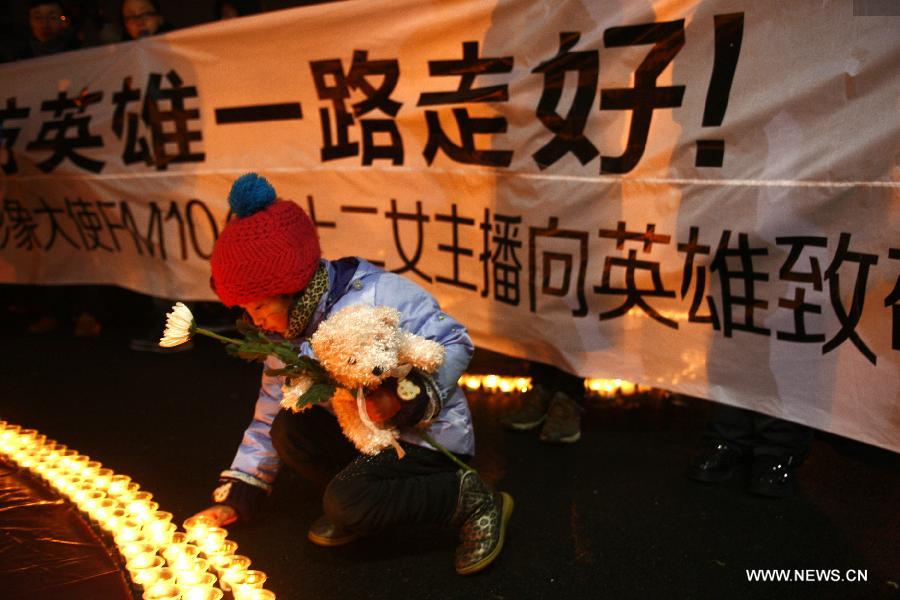 A girl lights the candles during a memorial service for the three firefighters who died while putting out fire in a factory blaze, at the Wushan Square in Hangzhou, capital of east China's Zhejiang Province, Jan. 7, 2013. Local citizens gathered here on Monday evening to mourn the three firefighters who sacrificed their lives while putting out a fire in Hangzhou's Xiaoshan District, six days after the fire broke out. The three firefighters, Yin Jinliang, Chen Wei and Yin Zhihui, were ratified as martyrs and awarded gold medals for their dedication to the national defence. They were also personally awarded the top-grade merit citation. (Xinhua/Cui Xinyu) 