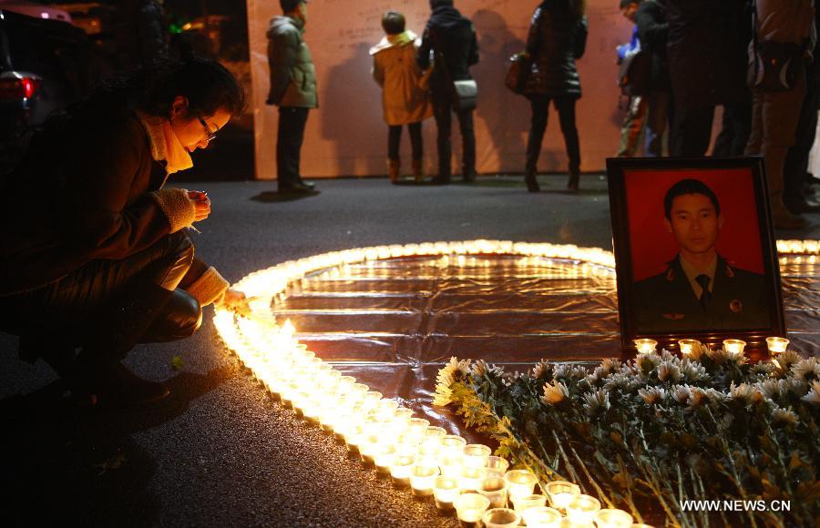 A woman lights the candles during a memorial service for the three firefighters who died while putting out fire in a factory blaze, at the Wushan Square in Hangzhou, capital of east China's Zhejiang Province, Jan. 7, 2013. Local citizens gathered here on Monday evening to mourn the three firefighters who sacrificed their lives while putting out a fire in Hangzhou's Xiaoshan District, six days after the fire broke out. The three firefighters, Yin Jinliang, Chen Wei and Yin Zhihui, were ratified as martyrs and awarded gold medals for their dedication to the national defence. They were also personally awarded the top-grade merit citation. (Xinhua/Cui Xinyu) 