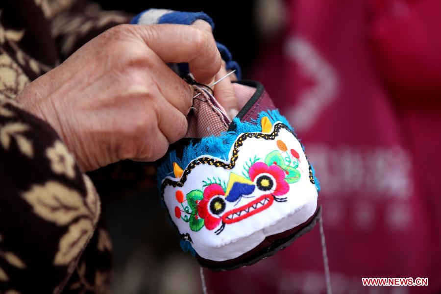 An old woman makes a tiger-head shoe in downtown Bozhou City, east China's Anhui Province, Jan. 7, 2013. Tiger-head shoes, a kind of traditional Chinese shoes made of colourful cotton fabric and thread, are popular for local people who hope their children grow as robust and healthy as tigers in the new year. (Xinhua/Liu Qinli) 