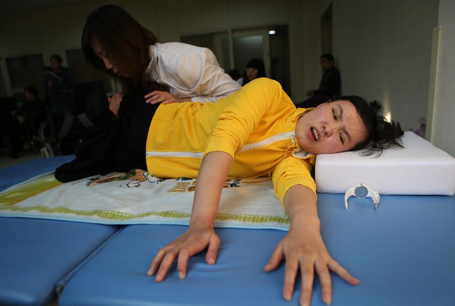 Zhang Lili, a teacher who lost her legs while saving two students from an onrushing bus, does rehabilitative training under the help of a doctor at the China Rehabilitation Research Center in Beijing, capital of China, Jan. 7, 2013. Zhang, who successfully pushed the students out of the harm's way but unable to avoid the bus herself and lost her legs in the accident, has been receiving rehabilitative treatment here for over 4 months. Zhang makes great efforts now in order to be able to walk again. (Xinhua/Jin Liwang) 