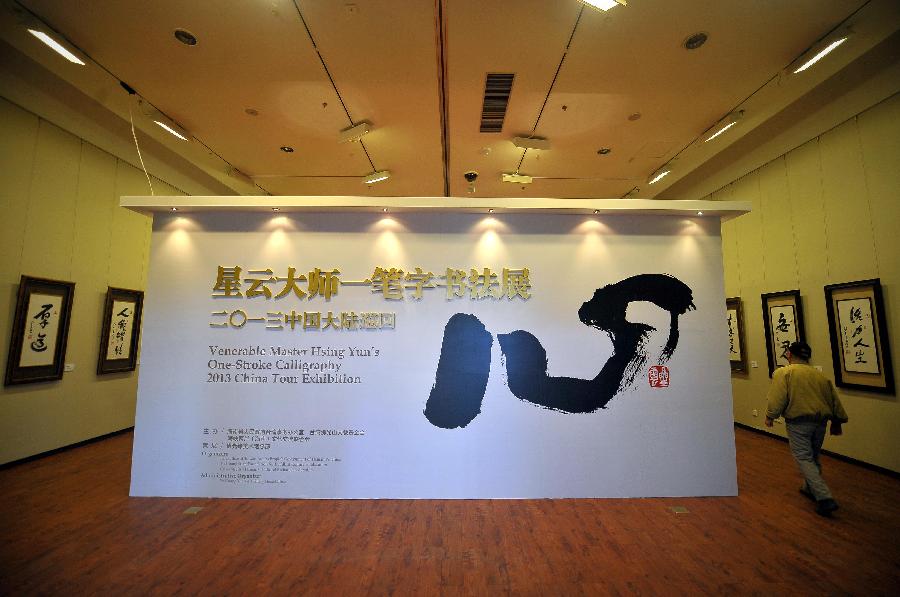 A visitor walks past a display board at a tour exhibition of Venerable Master Hsing Yun's One-Stroke Calligraphy held at the Hainan Provincial Museum in Haikou, capital of south China's Hainan Province, Jan. 8, 2013. A total of 55 calligraphy works by master Hsing Yun were on display at the exhibition that will last until Jan. 20. (Xinhua/Guo Cheng)  