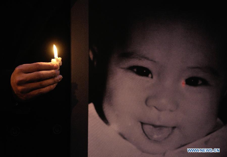 A relative of the victims holds a candle during a demonstration of the Chinese community to express their condolences to the victims and condemnation towards an armed robbery in Rome, Italy, Jan. 10, 2012. Zhou Zheng, a 31-year-old Chinese bar owner, and his baby daughter Joy were killed during the armed robbery in the Tor Pignattara area in Rome on Jan. 4, 2012. (Xinhua/Wang Qingqin) 