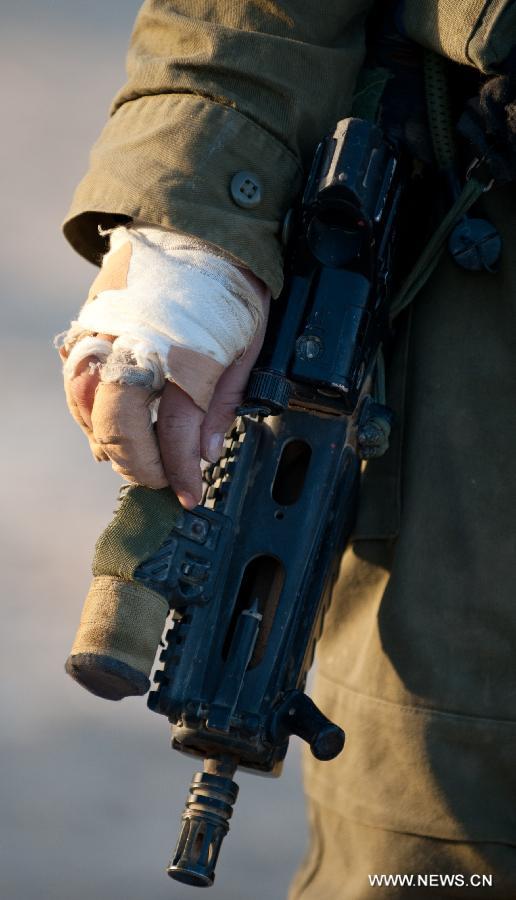 An injured Israeli woman soldier touches her gun during a military drill at the western part of Sede Boqer, southern Israel, on Dec. 13, 2012. (Xinhua/Yin Dongxun)