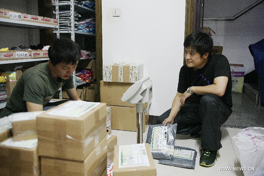 Photo taken on Oct. 12, 2012 shows an online shop owner Wang Hao (R) checking the orders with a delivery courier at home in Qingyanliu Village of Yiwu, east China's Zhejiang Province. (Xinhua/Huang Zongzhi) 