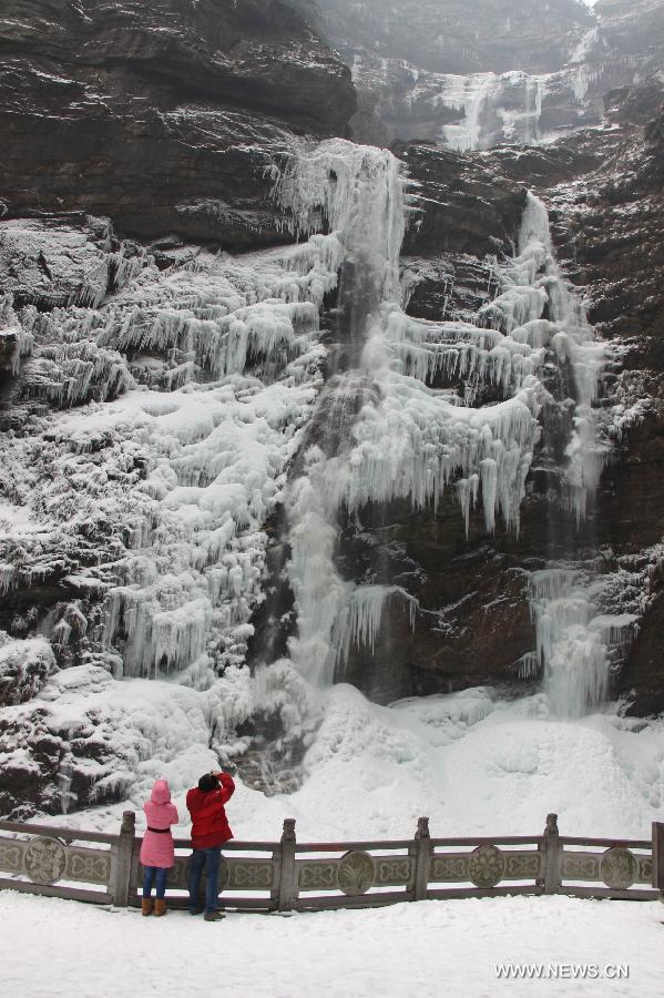 Two tourists take photos of a frozen waterfall in the Lushan Mountain in Jiujiang, east China's Jiangxi Province, Jan. 6, 2013. (Xinhua/Wei Dongsheng)