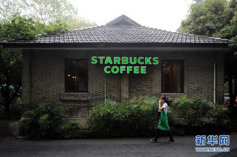 A Starbuck staff walks past the Starbuck café in Lingyin Temple on Sept. 22, 2012. Starbuck is a representative of coffee cultural in America, while Lingyin Temple embodies thousands years of Buddhism culture. Starbucks’ operation in Lingyin Temple has triggered hot discussion about excessive commercial development in historic place in China. (Xinhua/Ju Hanzong)
